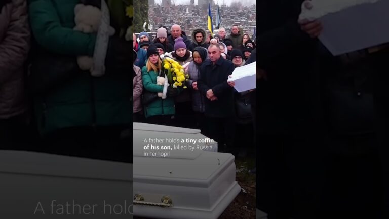 A father gently rocks the small coffin of his one-year-old son.