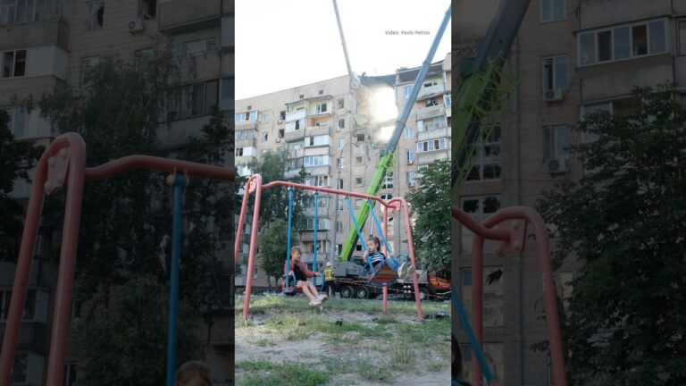 Children swing on a playground beside a building struck by a Russian attack in Kyiv on July 6